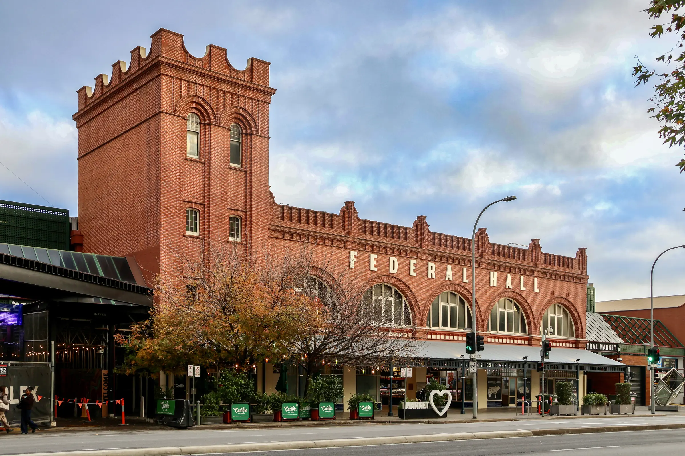 The Central Market's red brick Federal Hall on Grote Street, its crenellated tower and arched windows under a cloudy sky, autumn trees in front